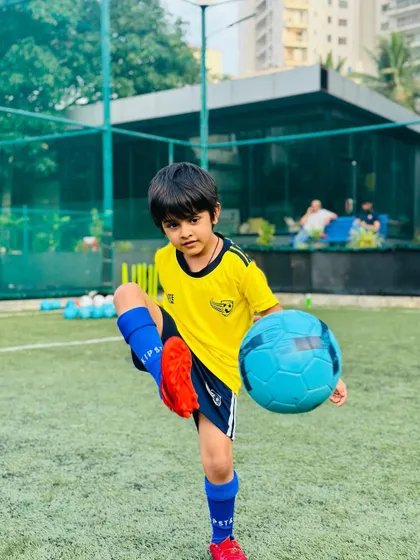 A young player poses with his football, full of confidence. We aim to build self-esteem both on and off the pitch.