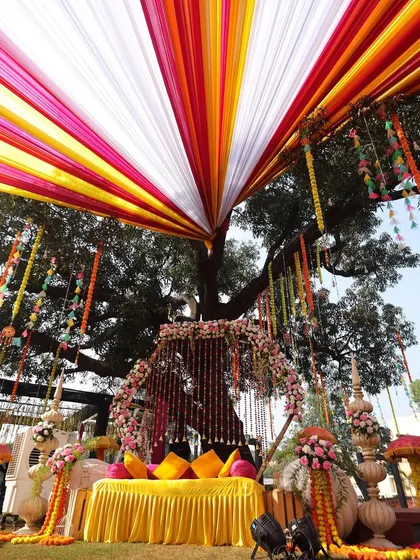 A memorable Haldi decor setup. This wide angle shows how we use colorful drapes radiating from a central point to create a stunning canopy effect over the entire event space.