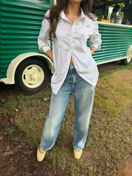 A close-up of the oversized white shirt, which has subtle embroidery details.