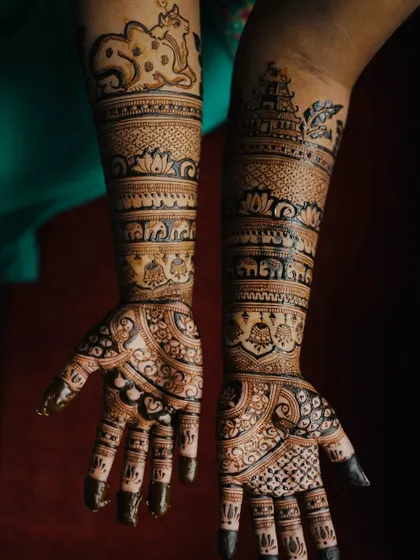 This South Indian bridal design is rich with personal and cultural symbols, including temple gopurams, elephants, and a sacred cow with its calf (Nandi).