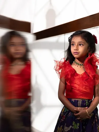 A thoughtful portrait of a young girl at a housewarming event, her reflection creating a sense of depth and story.