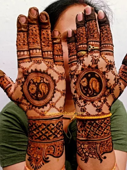 A happy client showing off her full bridal mehandi. The design features peacock motifs on the palms and extends up the arms with dense patterns.