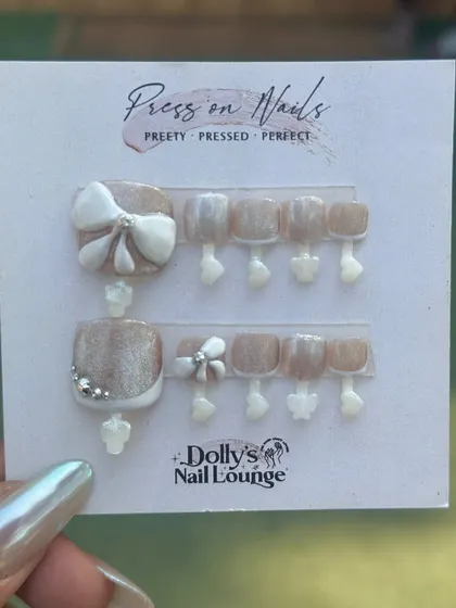 This press-on pedicure set is all about elegance. It features a shimmery nude base with a white French tip on the big toe, adorned with a 3D bow and silver gem accents.