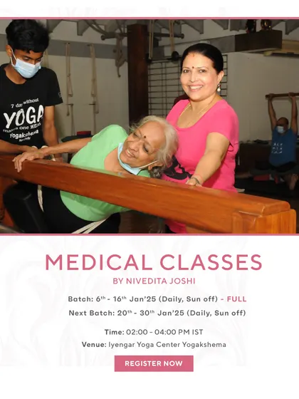 An elderly student is being guided in a supported forward bend. This shows that my medical classes are for every age and condition, providing a safe and effective way to manage pain and improve mobility.