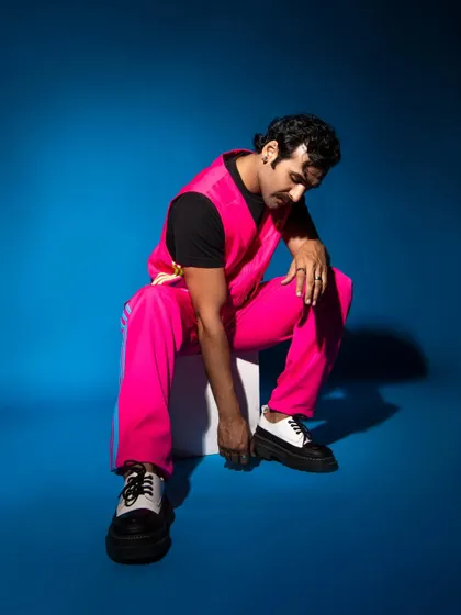 The combination of the bright pink athleisure wear and the bold blue background creates a vibrant, color-blocked fashion statement.