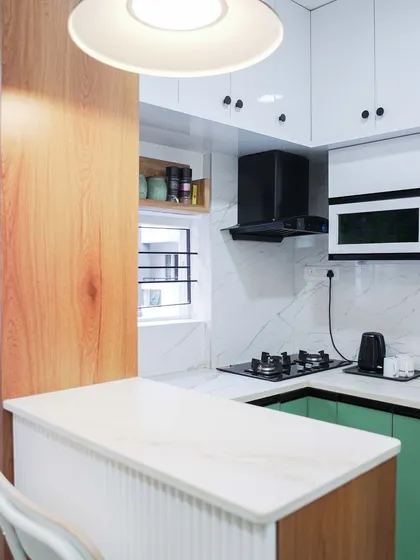 An open-plan kitchen and breakfast bar in a striking green and white color scheme. The fluted texture on the bar counter and the modern pendant light make this a stylish and social hub of the home.