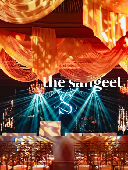The stage for the Sangeet in Cannes, featuring the couple's monogram, dramatic lighting, and flowing drapes, ready for a night of epic performances.