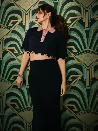 A full-length shot that showcases the entire navy and pink co-ord set against the striking green wallpaper. The color combination is fantastic.