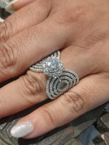 The beauty of a custom diamond ring on the hand. This piece, with its sparkling 1-carat solitaire and intricate pavé band, is crafted in 18kt gold and designed to be a cherished symbol for years to come.