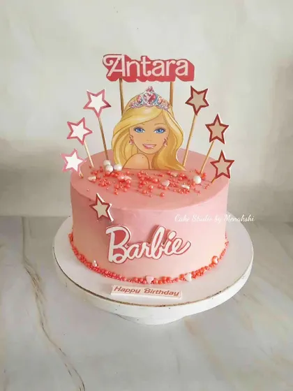 A pretty pink Barbie themed cake for a little fan. This no-fondant design is decorated with star toppers and a Barbie logo for a simple yet fun look.
