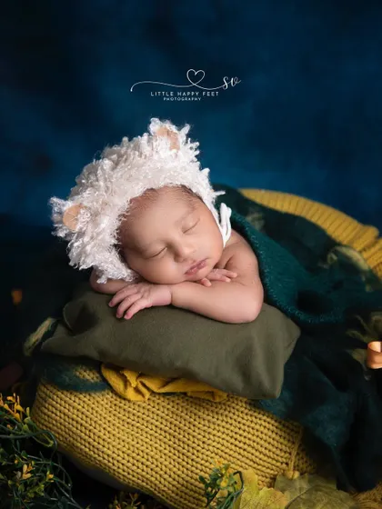 Our little sheep, sound asleep. The textured bonnet and cozy green and yellow blankets create a warm and pastoral scene.