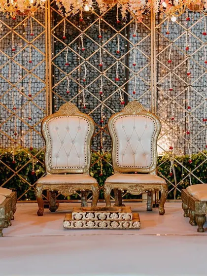 A close-up of the regal seating arrangement within the surreal mandap, featuring ornate golden chairs and a crystal-studded backdrop.