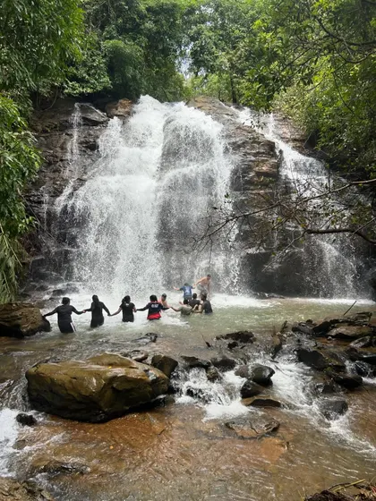 Holding hands to form a human chain for safety and fun while enjoying the waterfall. Teamwork and looking out for each other is a big part of our trekking culture.