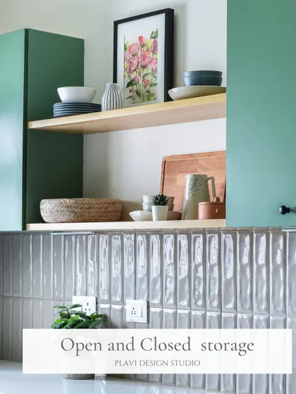 A mix of open and closed storage in this green kitchen allows for both practical hiding spots and beautifully styled shelves. The open shelf breaks up the cabinetry and provides a space to display favorite ceramics and art.