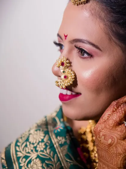 A close-up profile of the bride, highlighting her traditional Maharashtrian nose ring (nath) and flawless makeup.