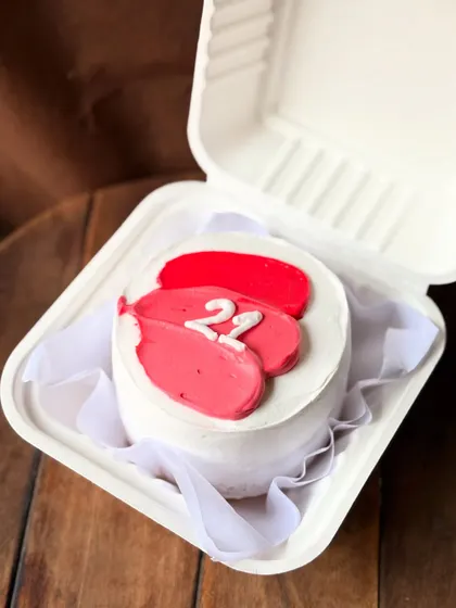 A pretty and minimalist bento cake with pink and red abstract brushstrokes. The number "22" is piped in the center, making it a chic and modern birthday cake.