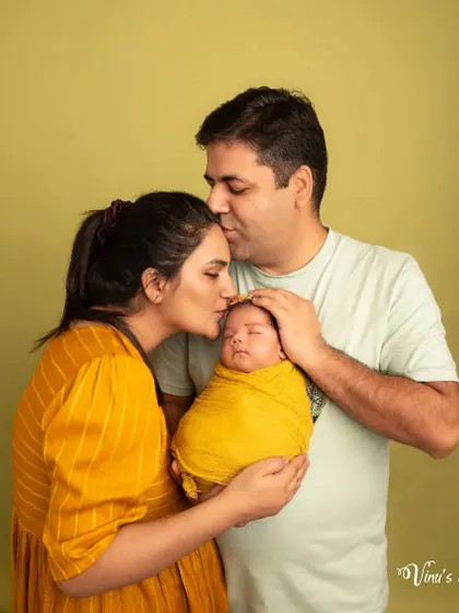 Kisses for the new arrival. This portrait captures the parents lovingly kissing their newborn's head, a beautiful symbol of their new journey as a family of three.