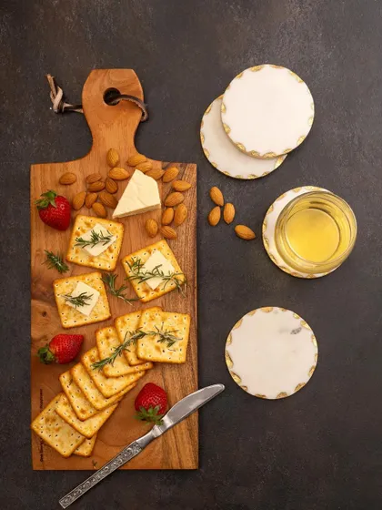 A dark and moody flat lay of a cheese board, styled with crackers, strawberries, and almonds. This top-down shot is dramatic and highlights the texture of both the food and the wooden board.