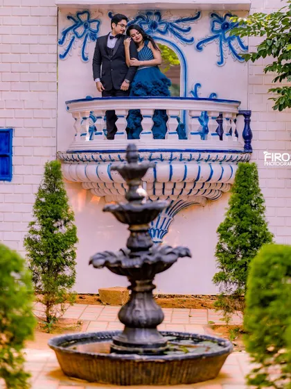 A "Romeo and Juliet" style shot on a beautiful blue and white balcony. The couple looks out from above, creating a classic, storybook feel for their pre-wedding shoot.