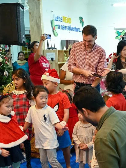 The Christmas party is in full swing, with children, parents, and teachers mingling and celebrating together.
