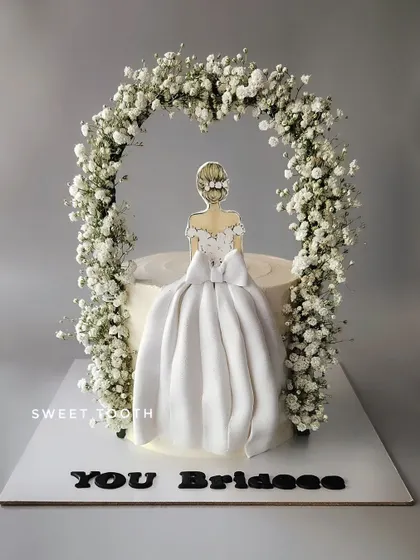 A cake for the bride-to-be. This beautiful blueberry cake features a fondant gown and a fresh baby's breath arch, perfect for a bridal shower.