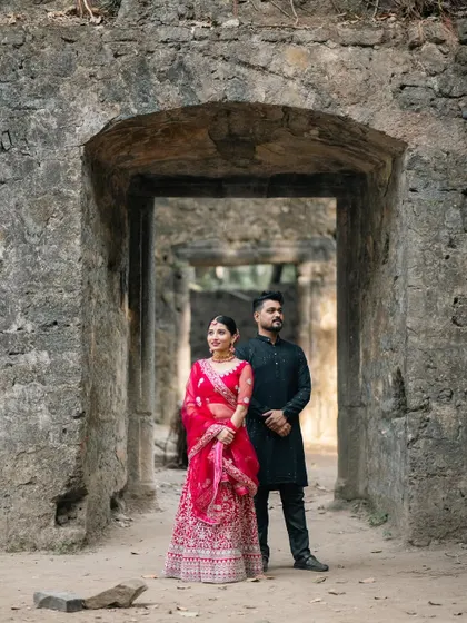 A powerful pre-wedding portrait of a couple standing in the archway of an ancient stone fort, their traditional outfits creating a stunning contrast.