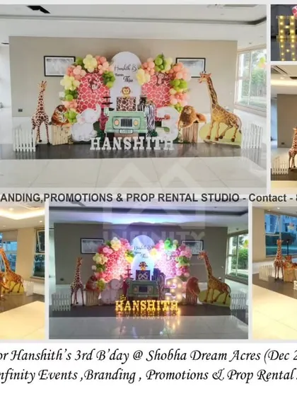 A "Wild Three" safari theme for a 3rd birthday at Shobha Dream Acres. This setup includes a backdrop with a pink and green balloon garland, various stuffed safari animals, and a light-up number "3" to mark the milestone.