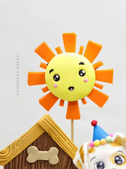 A detailed shot of the smiling sun topper from the pet-themed cake. Even simple shapes can be given a lot of personality with the right techniques.