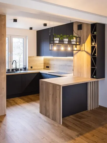 This U-shaped kitchen features a small peninsula that functions as a breakfast bar. The matte black and wood-laminate finish gives it a bold, industrial-chic look.