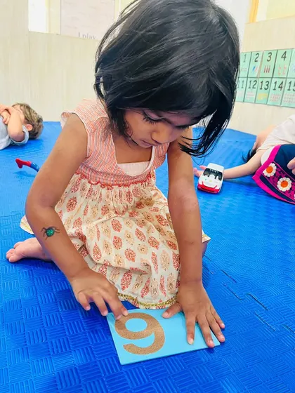 This child is practicing tracing the number 9, building the muscle memory needed for writing numerals.