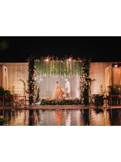 A stunning wide shot of the wedding mandap set over a pool. The reflection in the water adds a magical and grand feel to the ceremony.