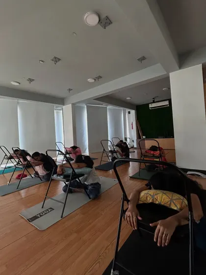 Students use chairs for support during a restorative pose in our PCOD/PCOS workshop. Gentle, supported poses are key for stress reduction.
