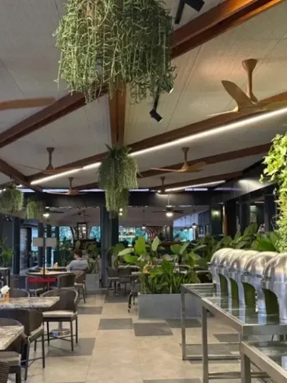 A large vertical garden serves as a backdrop for the café's buffet area. This living wall not only enhances the aesthetic but also improves air quality and absorbs sound, contributing to a more pleasant dining experience.