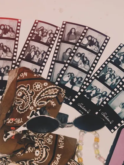 A stylish flat lay of photo strips, sunglasses, and a bandana, showing how these prints become part of your personal aesthetic.