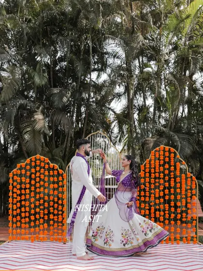 A posed shot of the couple against a backdrop of marigolds at their Goa Haldi.