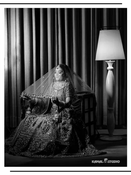 A timeless black and white portrait of the bride seated, her veil creating a soft, ethereal frame.