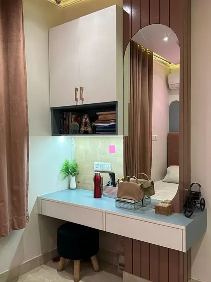 A functional and stylish dressing table with an arched mirror and fluted paneling. The design includes drawers and overhead storage for cosmetics and accessories.