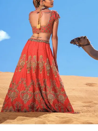 A whimsical and unique shot featuring the bride in her zardosi lehenga in a desert landscape, creating a stunning contrast of color and texture.