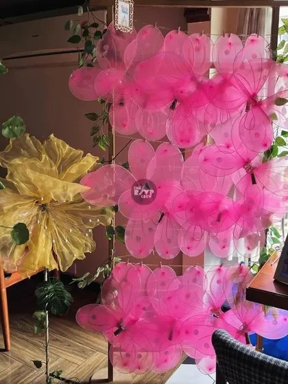 A beautiful wall of translucent pink and yellow flowers and fairy wings, creating a perfect photo opportunity at this enchanted garden party.