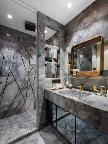 In this Mumbai residence, the bathroom is transformed into a private sanctuary of 'marbelous' splendour. We enveloped the space in dramatic grey marble, using its natural veining as a form of art. The custom brass-framed mirror and integrated sink demonstrate our focus on bespoke details and material excellence.