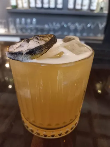 A whiskey sour with a dehydrated lime garnish, a simple yet sophisticated choice for any cocktail menu.