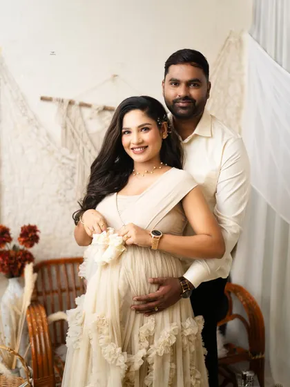 A sweet and simple portrait. The couple holds up a pair of tiny baby shoes, a classic and heartwarming way to symbolize their growing family.