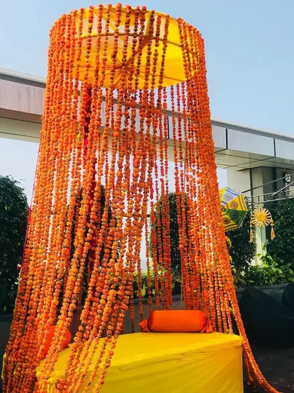 A unique seating idea for a Haldi ceremony, with a canopy made of hanging marigold strings.