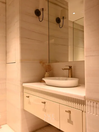 This powder bathroom design focuses on texture and light. The fluted details on the floating vanity, paired with soft wall sconces and a vessel sink, create a small space that leaves a big impression.