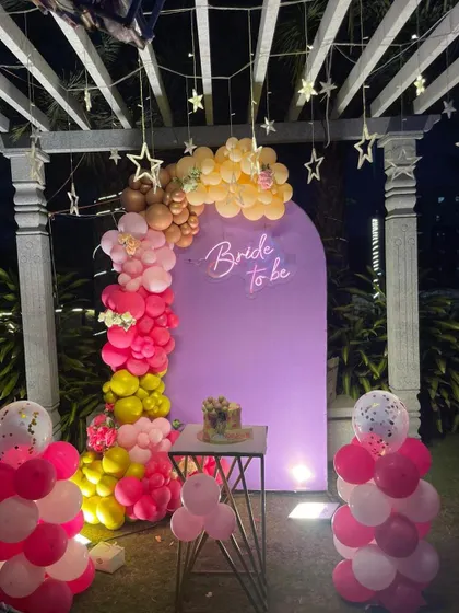 A full view of our popular purple-themed "Bride to be" decoration, set up outdoors under a pergola with hanging star lights. The design includes a colorful balloon garland and a small table for the cake.