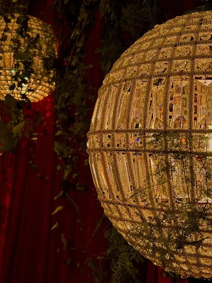 A close up of the unique crystal-and-jute spherical lanterns used in this wedding decor. These elements add a touch of modern artistry to the classic red and green theme.
