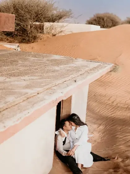 An intimate moment shared in a sand-swept structure in the Abu Dhabi desert. This cozy, sheltered shot contrasts with the vastness of the surrounding dunes.