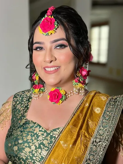 A beautiful Mehendi look with a focus on glowing skin and defined eyes. The floral jewelry adds a traditional and festive touch.