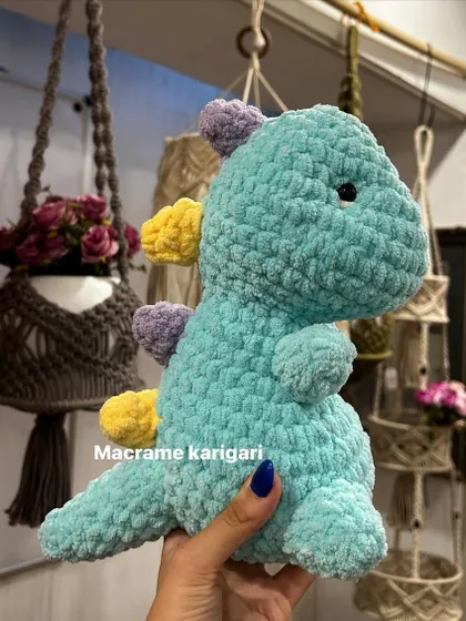 A side view of our chunky yarn dinosaur, showcased against a backdrop of our other macrame creations. It’s a sturdy, well-crafted toy ready for hours of play.