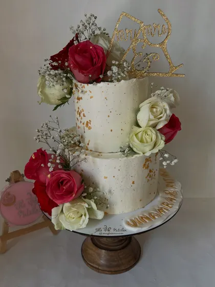 I designed this rustic two-tier cake specifically for a Roka ceremony, complete with a custom topper. The textured buttercream, gold dust speckles, and arrangement of fresh red and white roses create a chic and celebratory look.